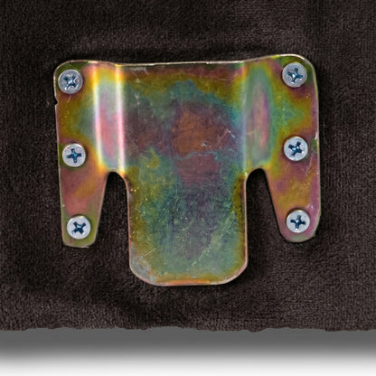 Close-up of iridescent metal bracket on dark upholstered surface