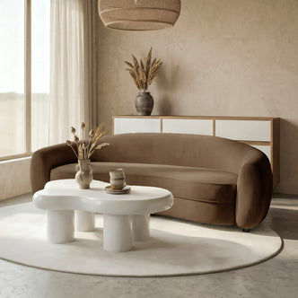 Brown curved sofa in a styled living room with coffee table and decor