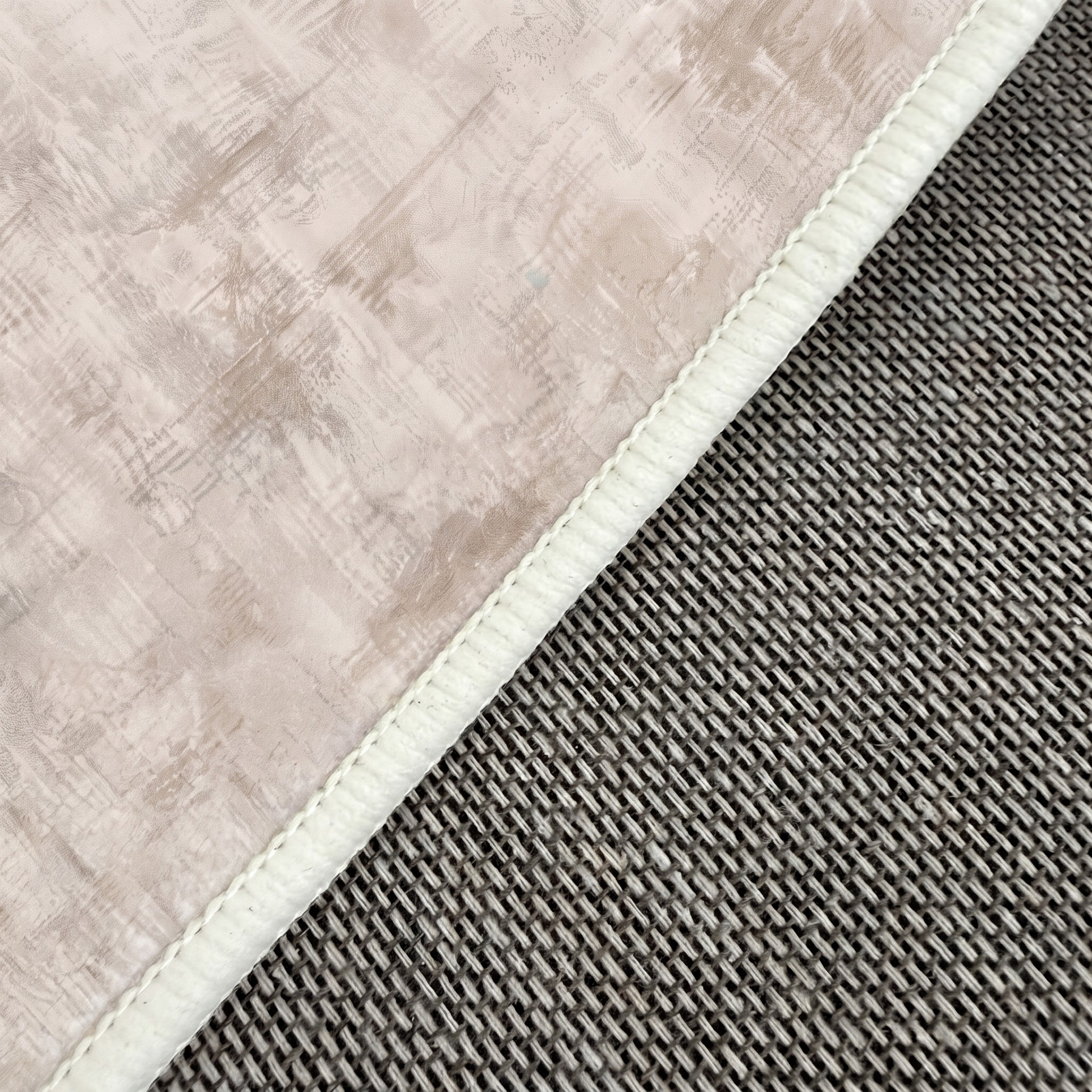 Close-up of beige textile edge and stitching on a gray textured surface
