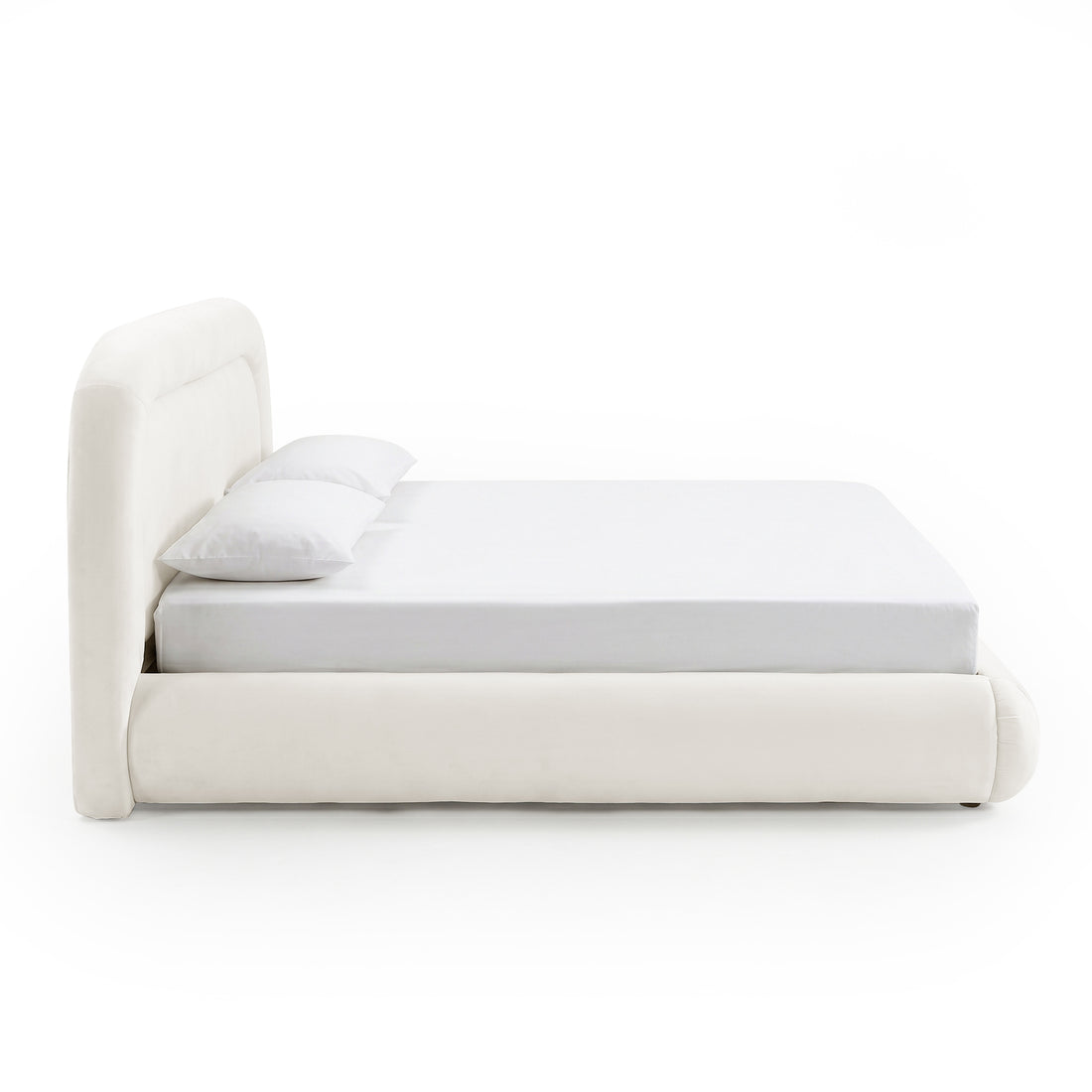 Side view of upholstered bed with mattress and pillows on white background