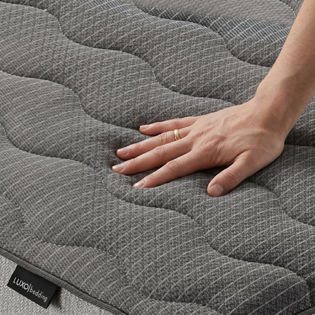 Hand pressing textured mattress surface close-up