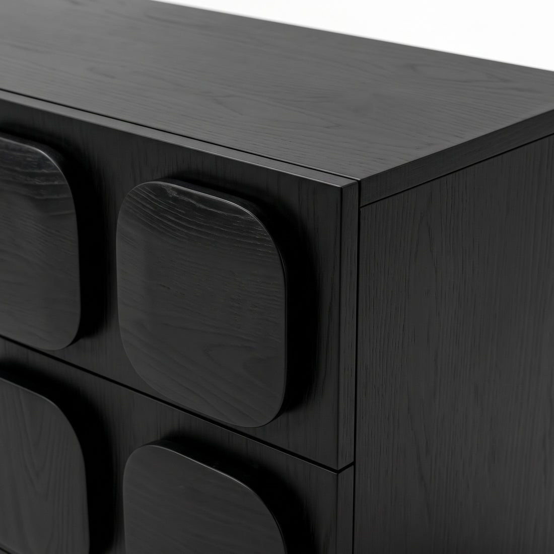 Close-up of a black wooden dresser corner with geometric drawer fronts
