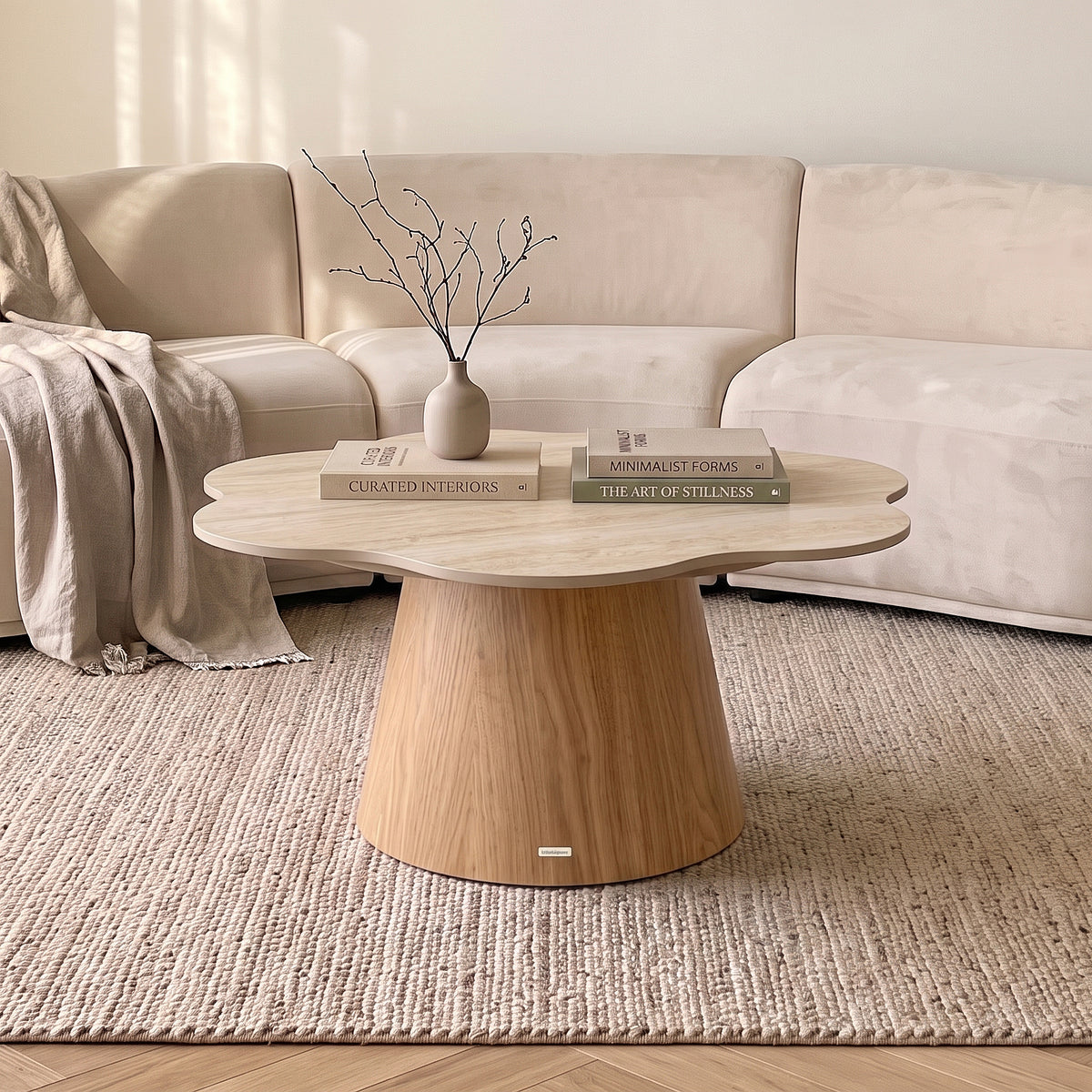 Modern round coffee table styled in a living room with sofa, rug, books, and vase