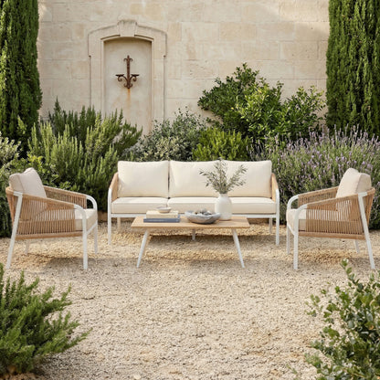 Vernon Outdoor Cushion Covers Set of 5 in Cream White transform the patio's woven-rope armchairs and sofa with sleek, weather-ready covers, enhancing the serene setting against a lush, green Mediterranean backdrop.