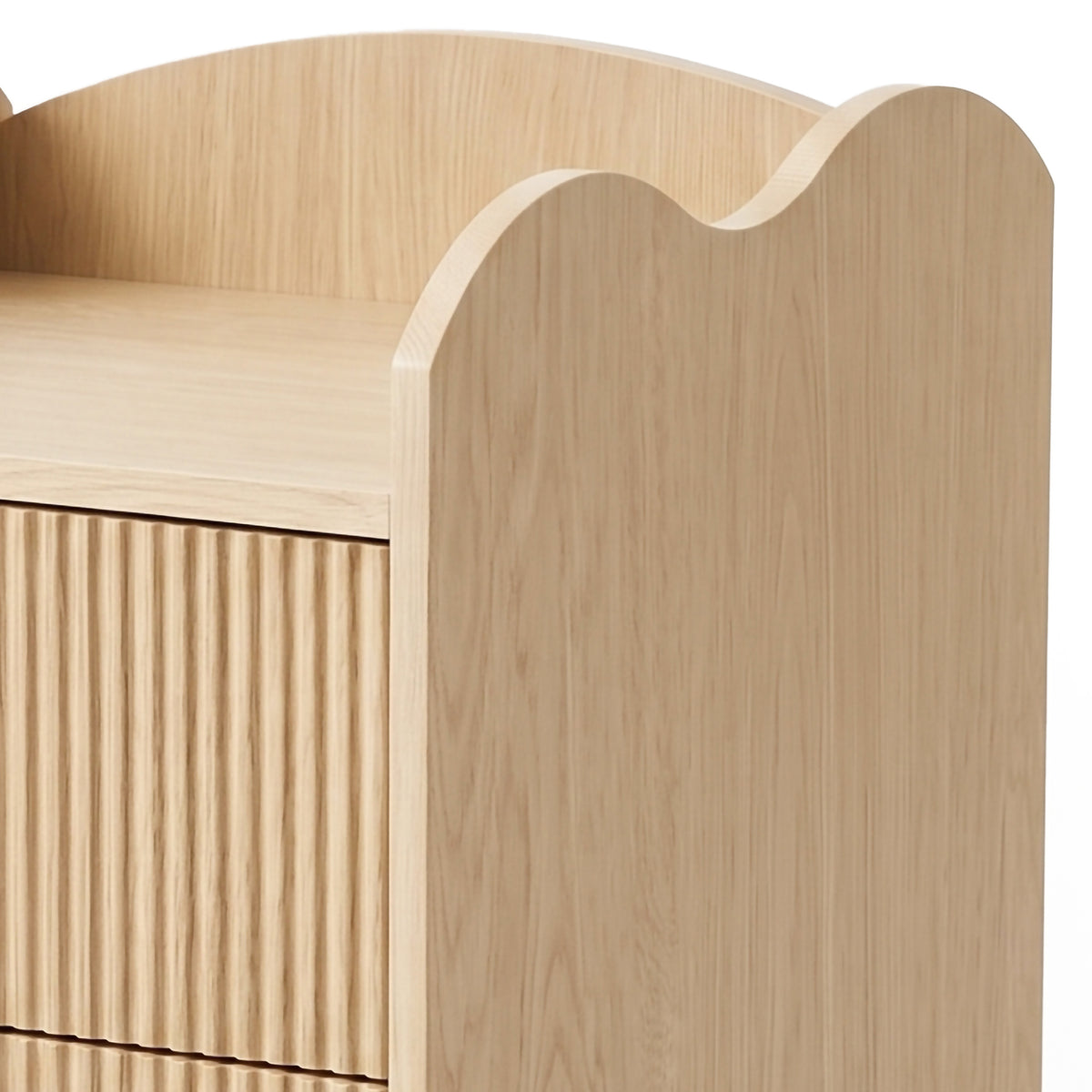 Partial view of light wood cabinet with scalloped back and ribbed door on white background