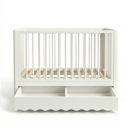 White baby crib on white background showing scalloped bottom edge and drawer