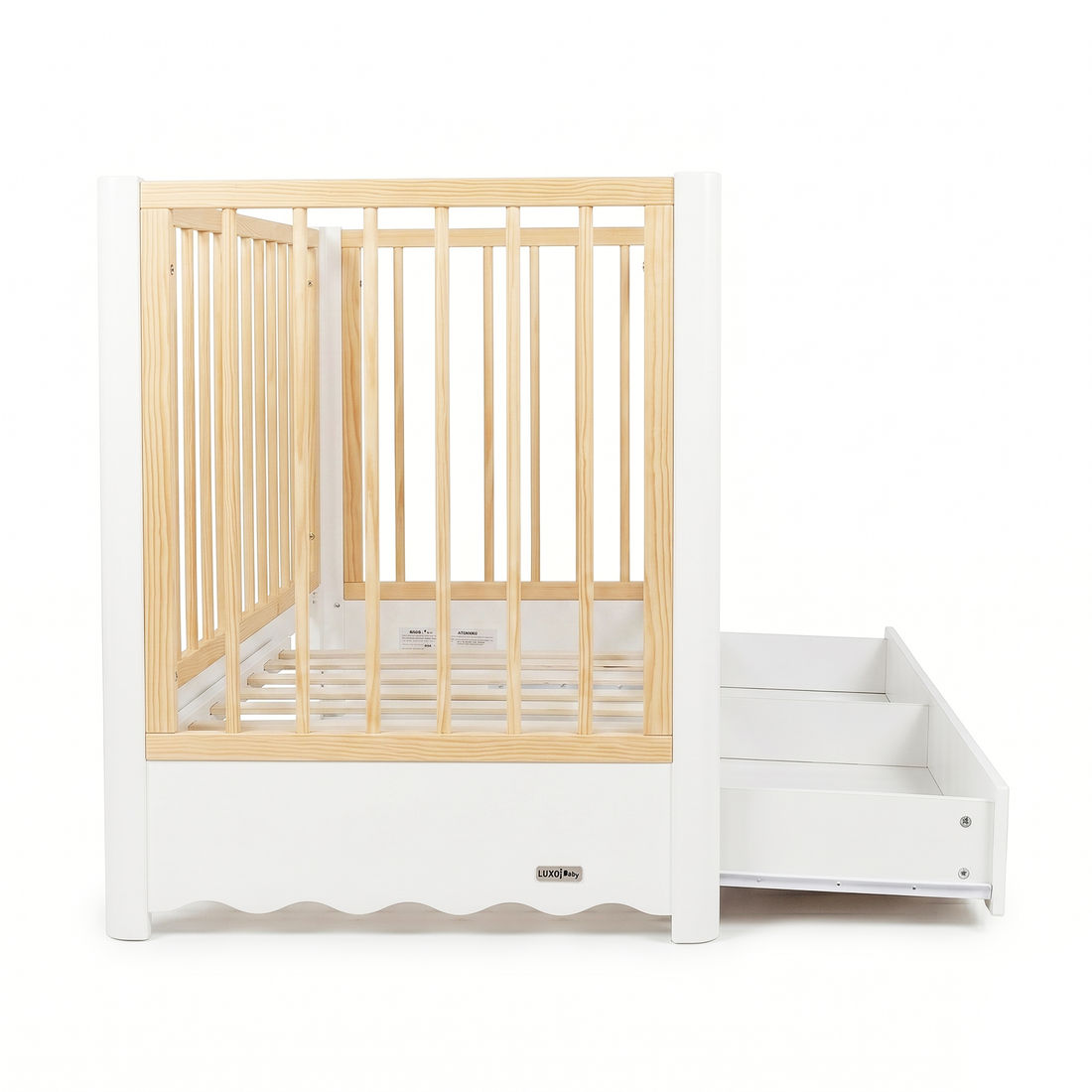 Modern white and natural wood baby crib with attached drawer unit on white background