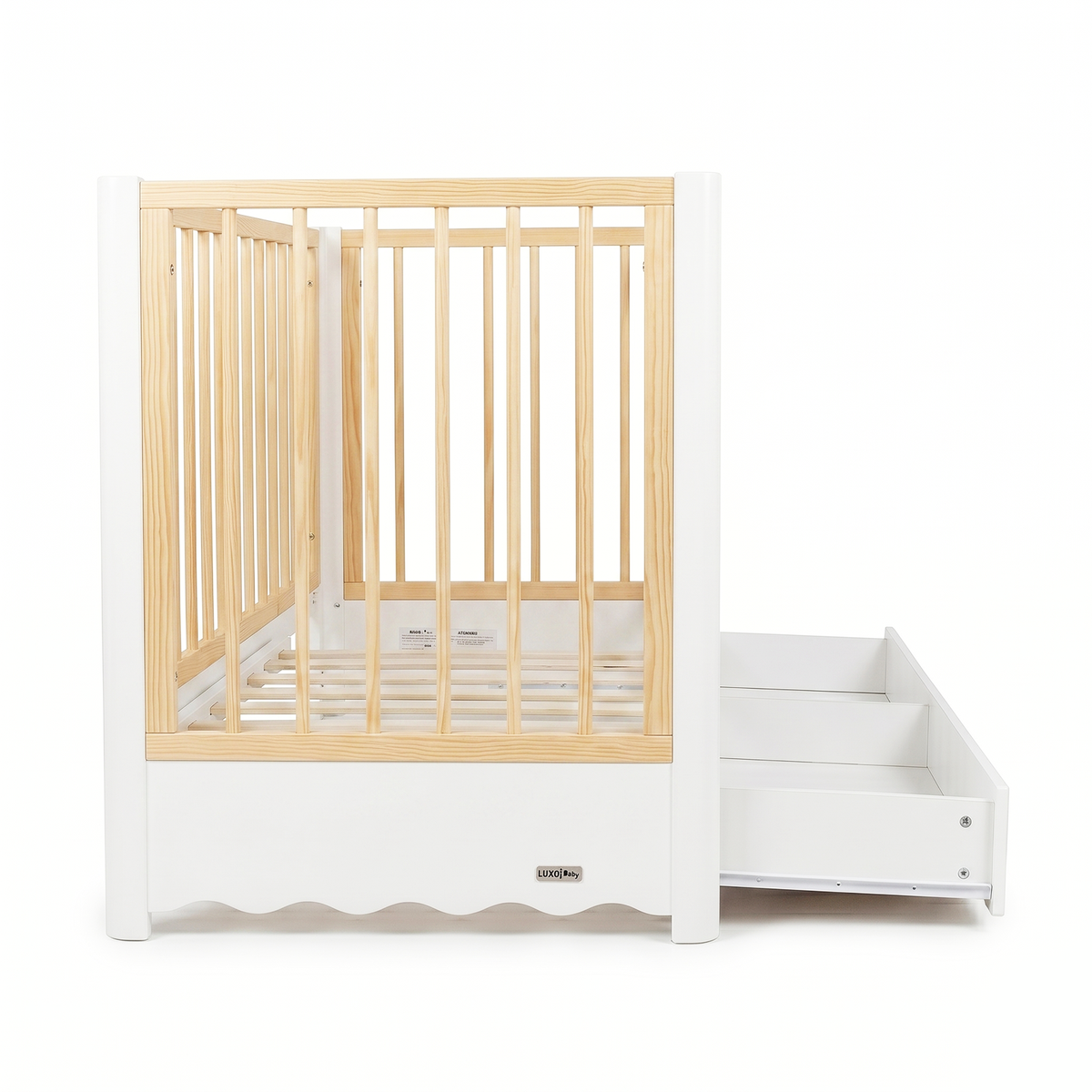 Modern white and natural wood baby crib with attached drawer unit on white background