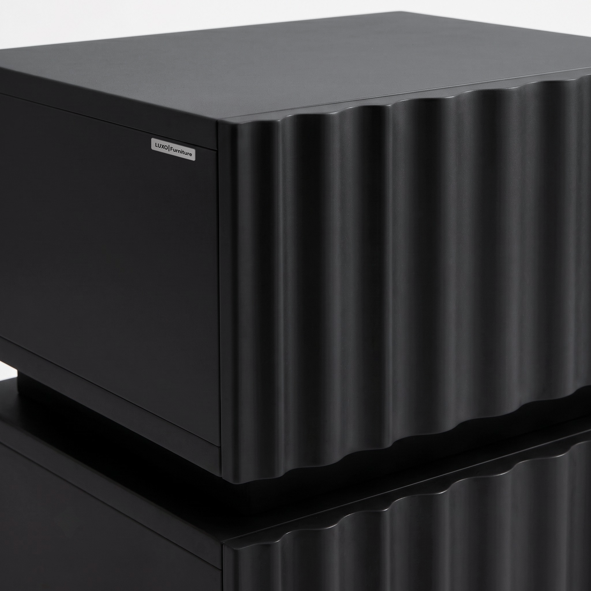 Partial view of a black textured cabinet with a wavy front on a white background.