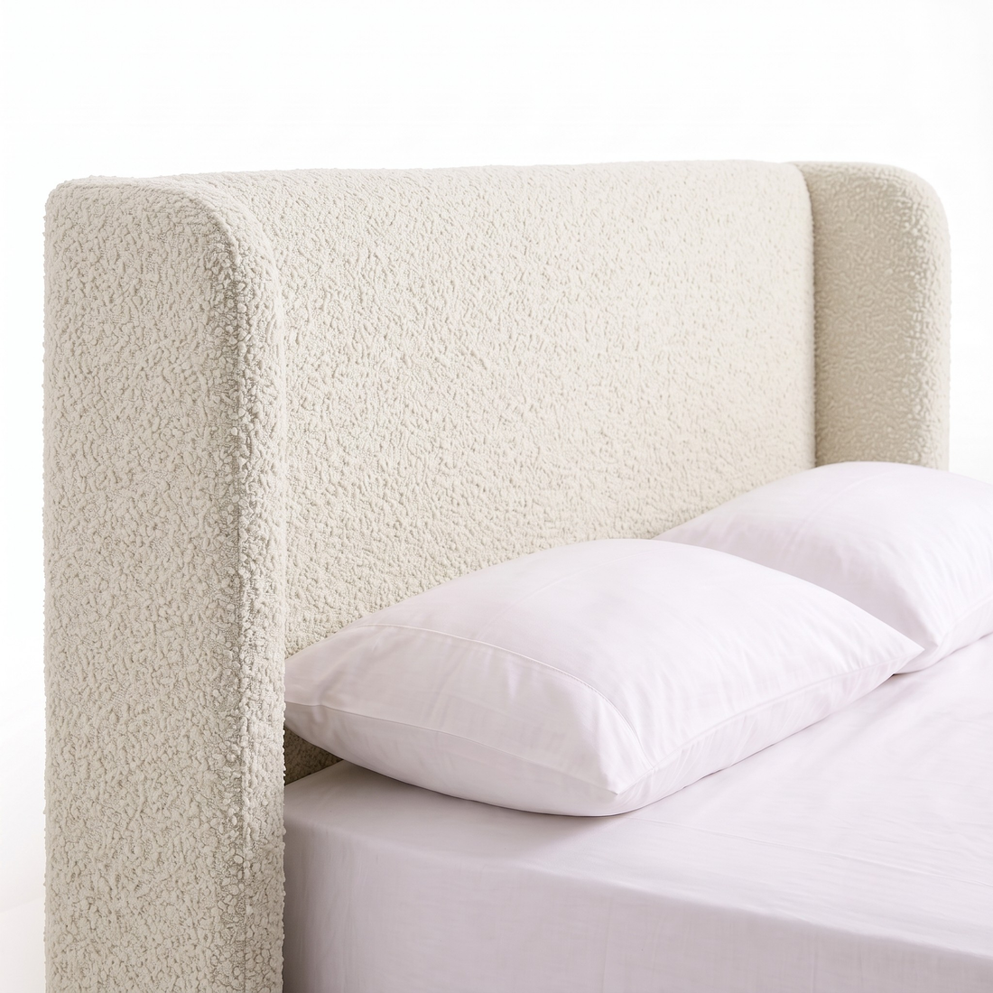 Close-up of upholstered bed headboard and pillows on a white background