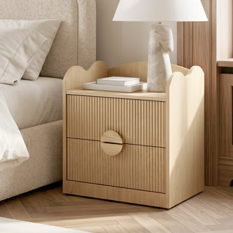 Light wood nightstand styled next to a bed in a contemporary bedroom