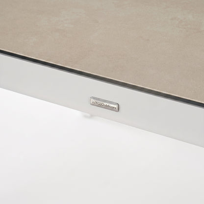 Close-up of the edge of a rectangular tabletop with a brand tag on a white background.