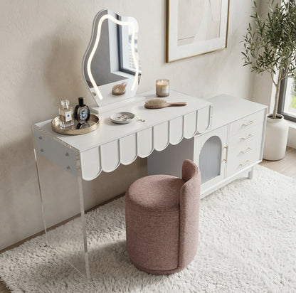 Lifestyle image of modern white vanity table with scalloped edge, LED mirror, and matching blush stool in a decorated room