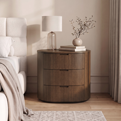 Wooden three-drawer nightstand styled in a bedroom next to a bed