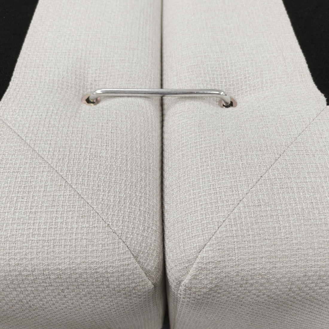 Close-up of a chrome connector between two beige upholstered sections