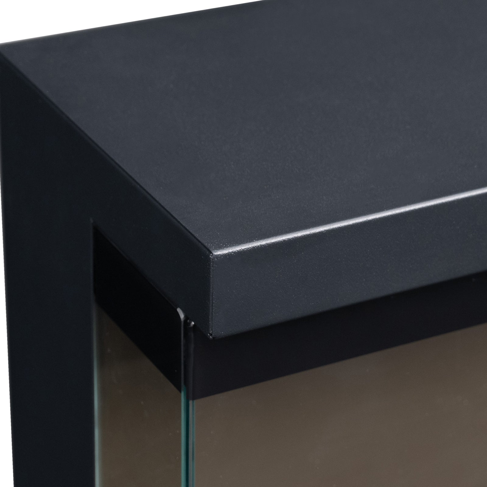 Detail shot of top front corner of electric fireplace on white background, showing black metal frame and glass.