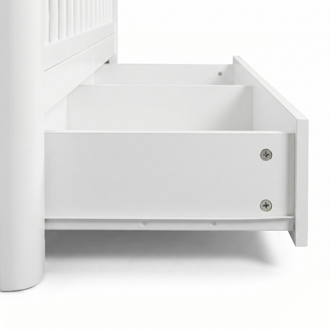 Close-up of bottom corner of white crib with open storage drawer on white background