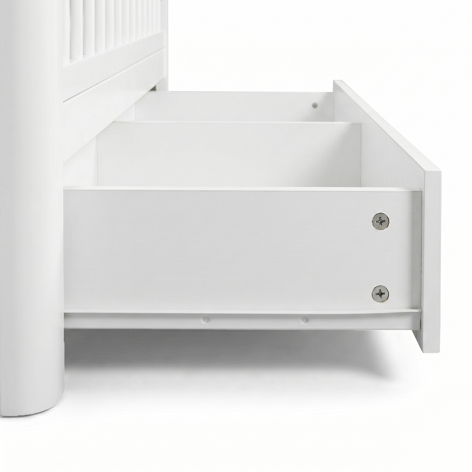 Close-up of bottom corner of white crib with open storage drawer on white background