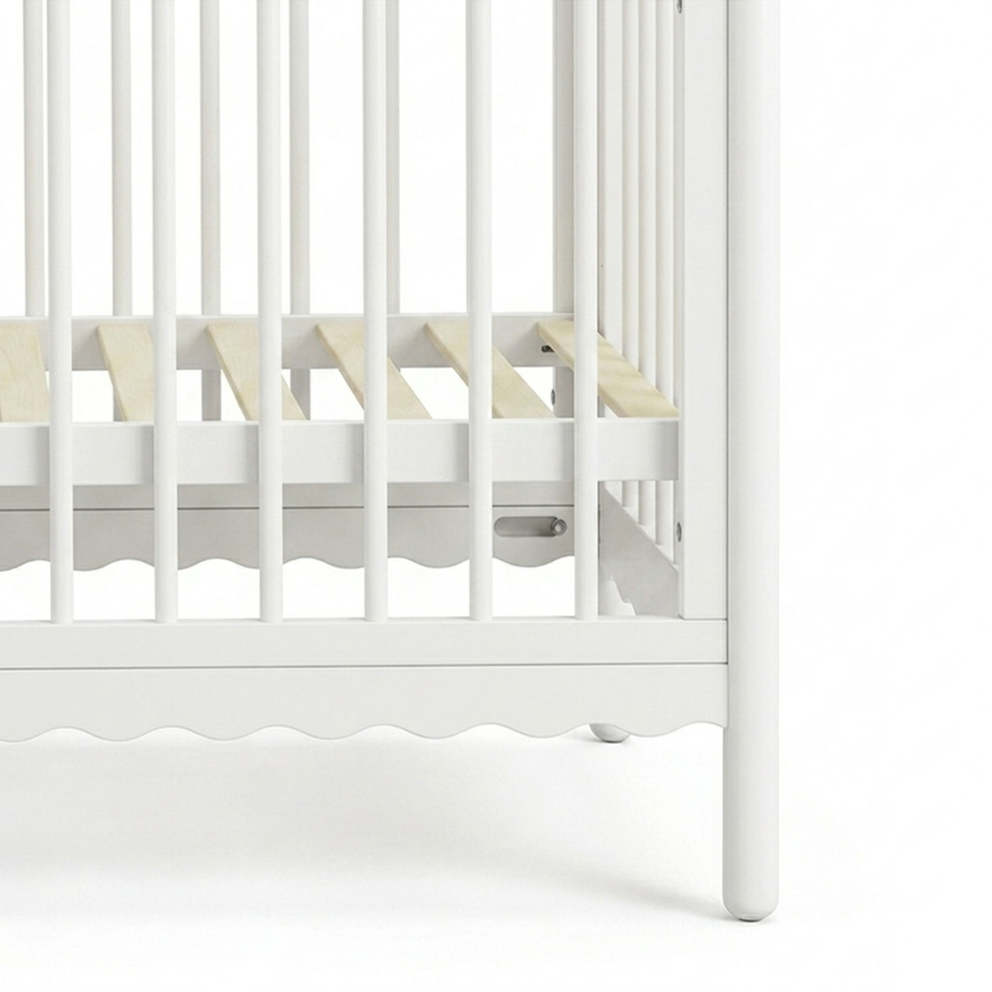 Close-up of lower portion of white wooden crib showing slats and corner