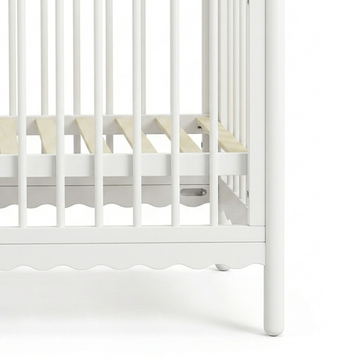 Close-up of lower portion of white wooden crib showing slats and corner