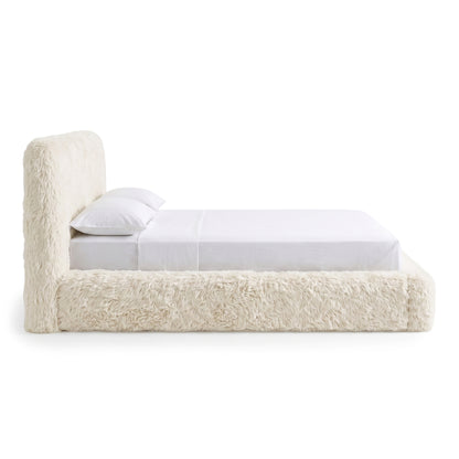 Side view of a cream upholstered bed on a white background.