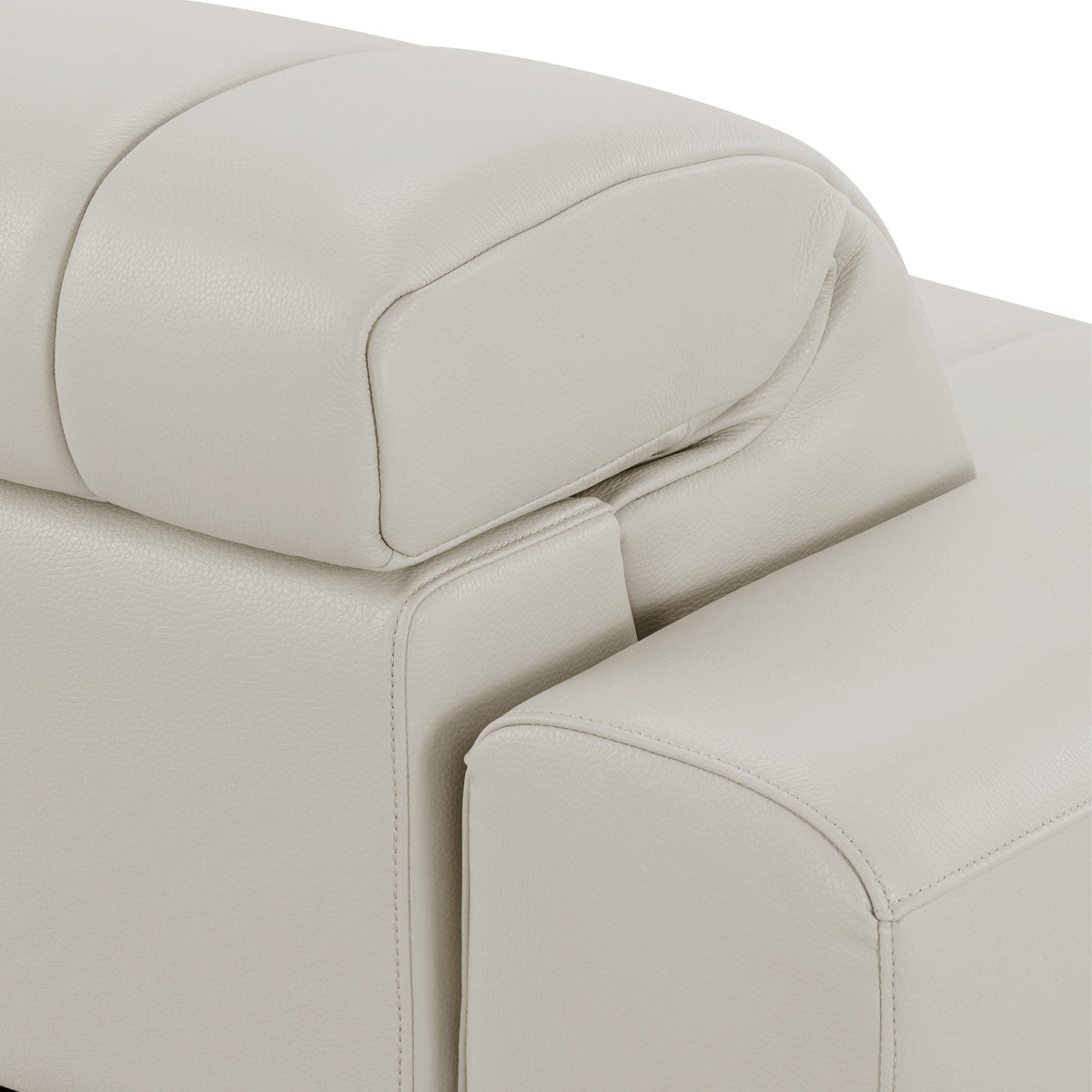 Close-up of a beige sofa armrest and headrest on a white background.