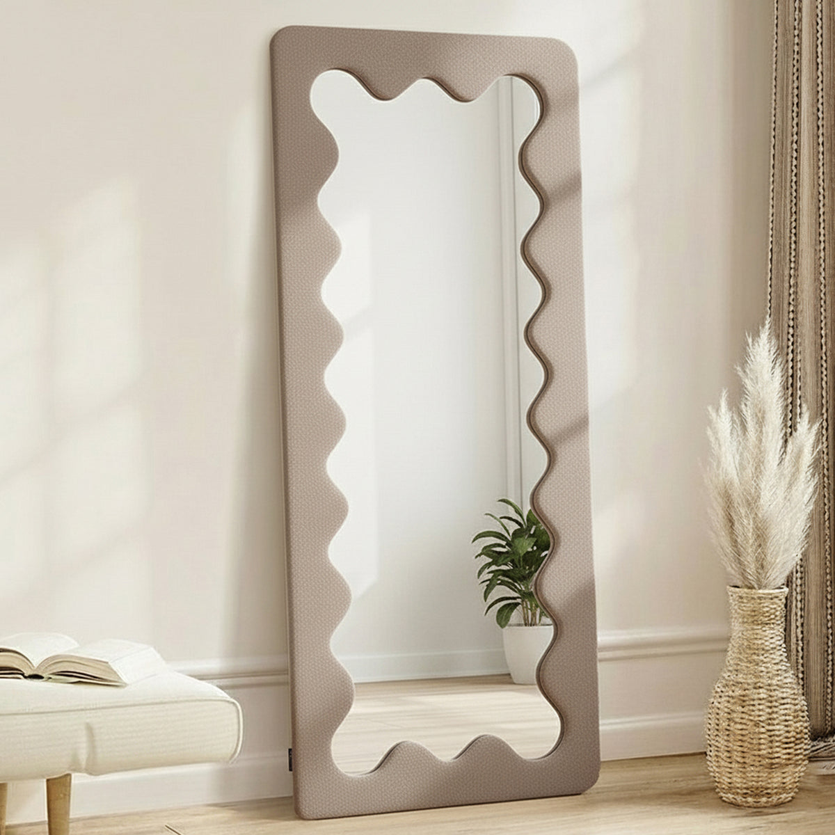 Serena 180cm Full Length Mirror in Taupe Brown with wavy-edged frame, styled with a bench, book, woven vase with dried grasses, and potted plant, creating a minimalist home decor vignette.