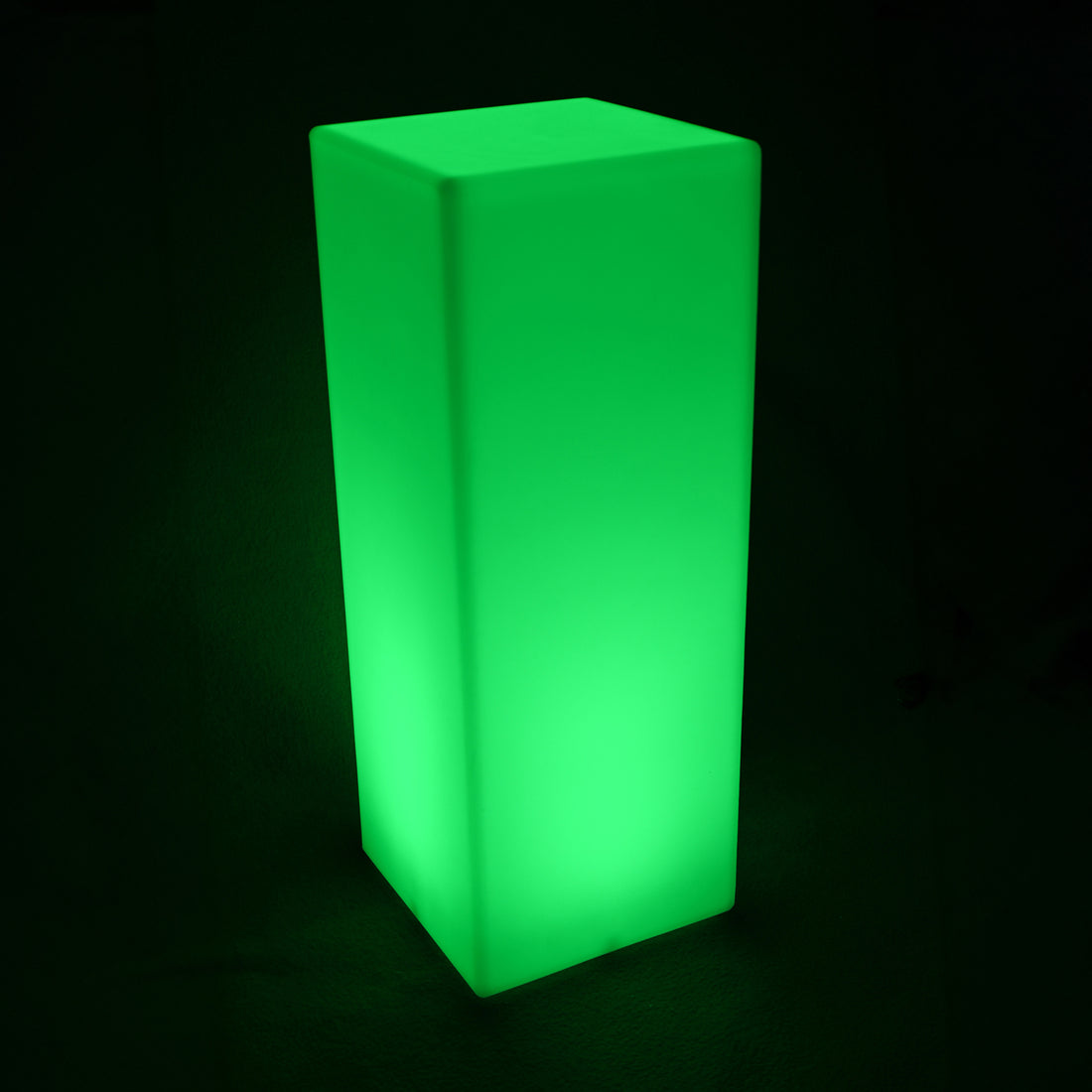 A glowing 80cm Outdoor Solar LED Column Light, shaped as a tall rectangular prism, emits a bright green light, highlighting its frosted-acrylic appearance in a dark setting.