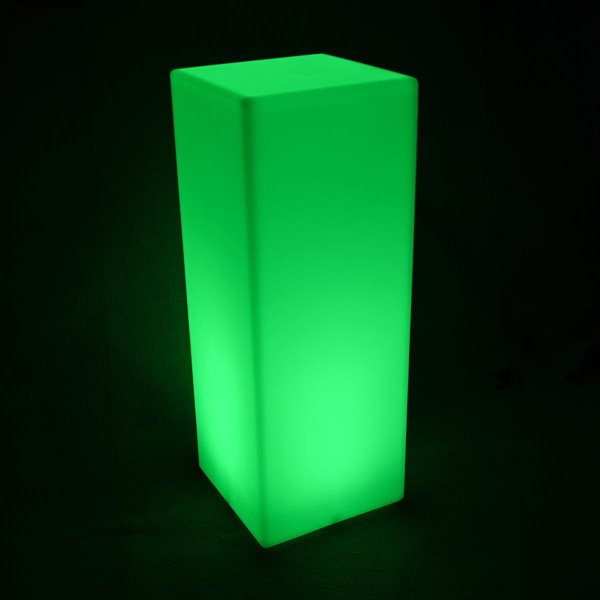 A glowing 80cm Outdoor Solar LED Column Light, shaped as a tall rectangular prism, emits a bright green light, highlighting its frosted-acrylic appearance in a dark setting.