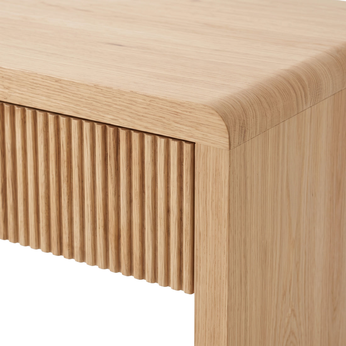 Close-up of a light oak desk corner with vertical groove detailing on a white background.