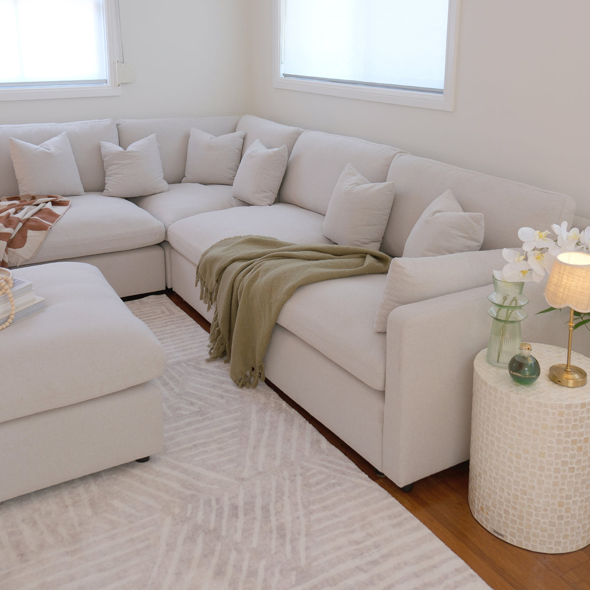 Light-colored sectional sofa with ottoman staged in a bright living room