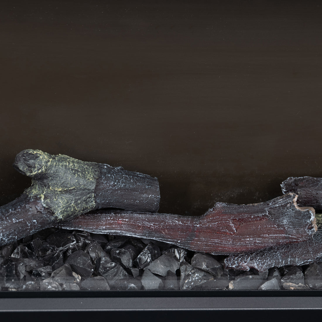 Close-up view of artificial logs and black stones inside an electric fireplace, showing texture detail.