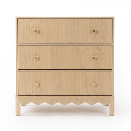 Three-drawer light wood dresser with gold flower knobs on white background