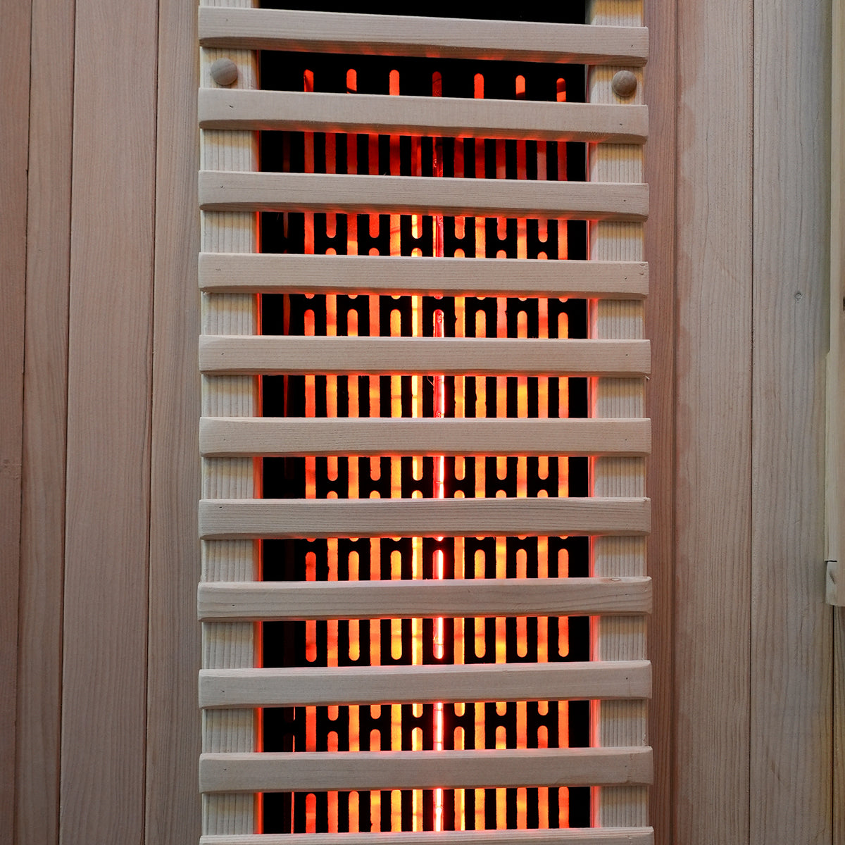 Close-up of a sauna heater with glowing heating elements behind a grill