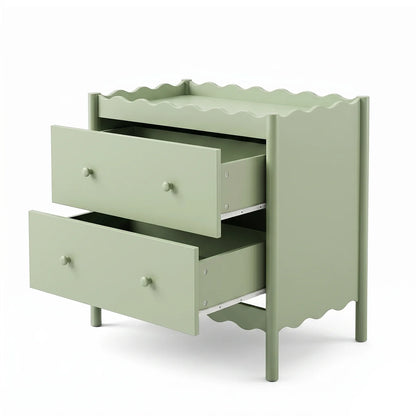 A sage green baby change table with two spacious drawers and a decorative scalloped trim along the top surface and base.